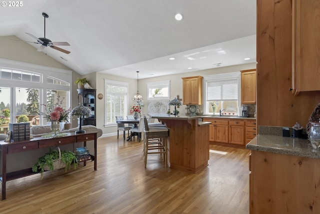 kitchen featuring pendant lighting, lofted ceiling, a breakfast bar, tasteful backsplash, and light hardwood / wood-style floors