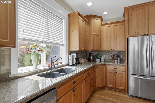 kitchen featuring light stone counters, stainless steel appliances, sink, and decorative backsplash