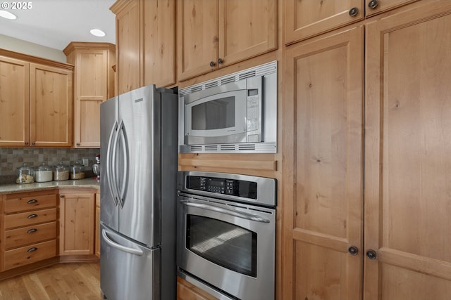 kitchen featuring appliances with stainless steel finishes, light brown cabinetry, backsplash, light stone countertops, and light hardwood / wood-style flooring