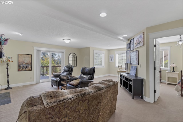 carpeted living room with a notable chandelier, a textured ceiling, and a healthy amount of sunlight