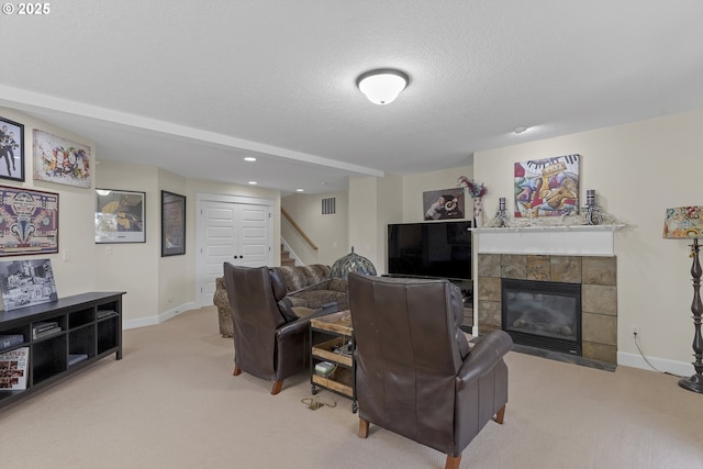 living room featuring a tiled fireplace, light carpet, and a textured ceiling