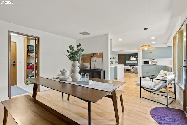 office with recessed lighting, a lit fireplace, light wood-type flooring, and visible vents