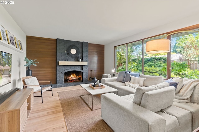 living room with light wood finished floors, a brick fireplace, and wooden walls