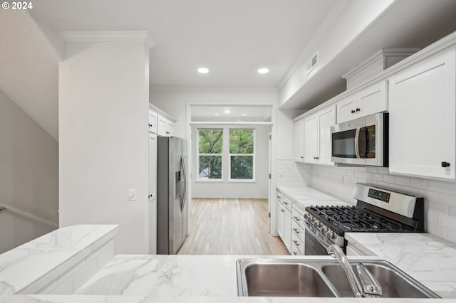 kitchen with decorative backsplash, light stone countertops, stainless steel appliances, white cabinetry, and a sink