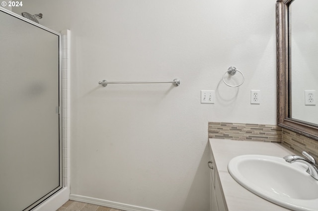bathroom with vanity, tasteful backsplash, baseboards, and an enclosed shower