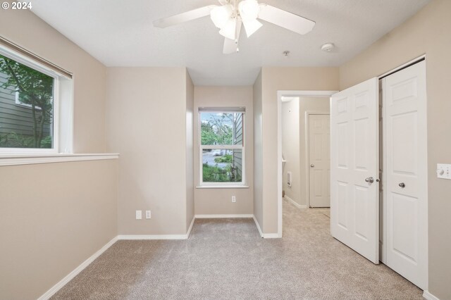 unfurnished bedroom with a ceiling fan, baseboards, and light colored carpet