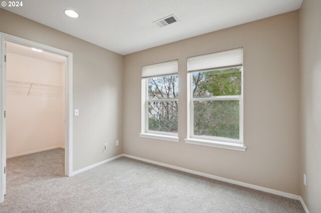unfurnished bedroom with a closet, visible vents, baseboards, light carpet, and a spacious closet
