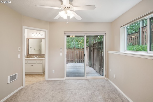 unfurnished room featuring carpet, baseboards, a sink, visible vents, and a ceiling fan