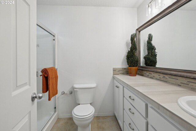bathroom featuring vanity, tasteful backsplash, toilet, a shower stall, and tile patterned floors
