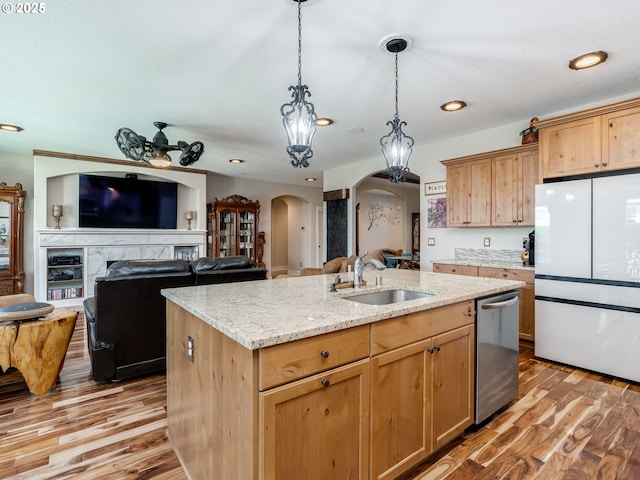 kitchen featuring arched walkways, a sink, open floor plan, freestanding refrigerator, and dishwasher