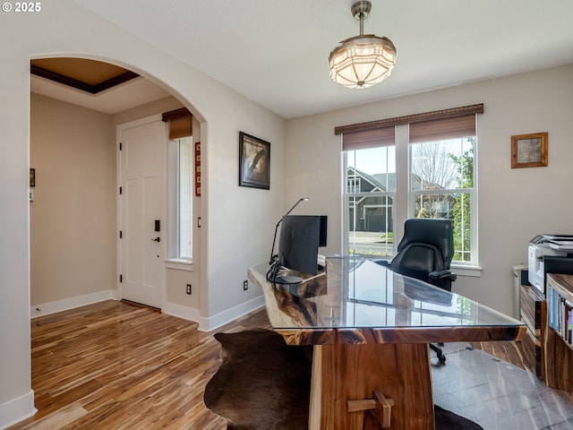 office space with wood finished floors, baseboards, and arched walkways