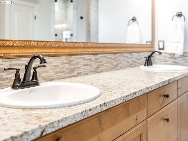 full bath featuring backsplash, a sink, and double vanity