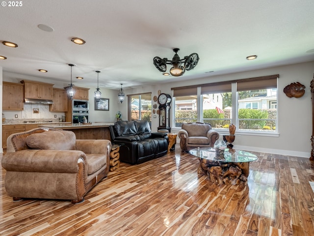 living area featuring baseboards, recessed lighting, and light wood-style floors