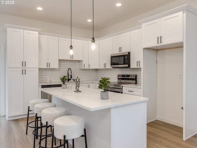 kitchen featuring white cabinets, stainless steel appliances, a sink, and light wood-type flooring