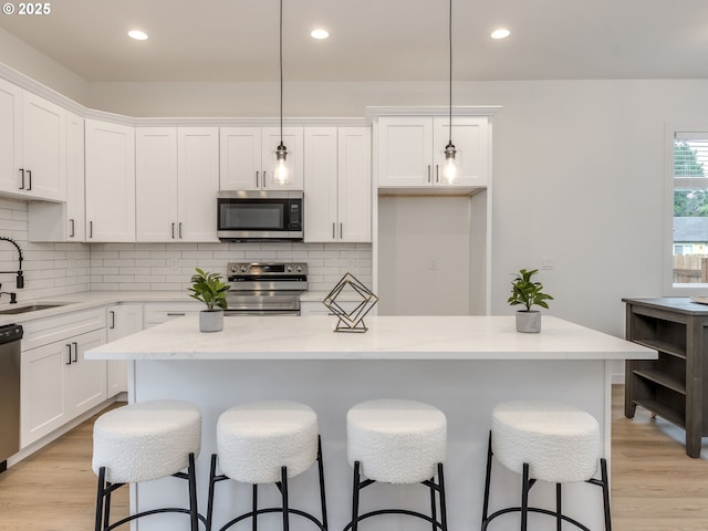 kitchen featuring white cabinets, stainless steel appliances, a sink, and light wood-style floors