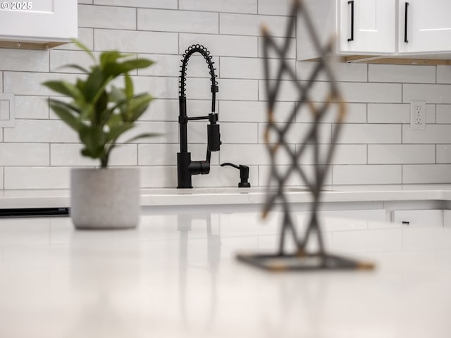 interior details with decorative backsplash and white cabinets