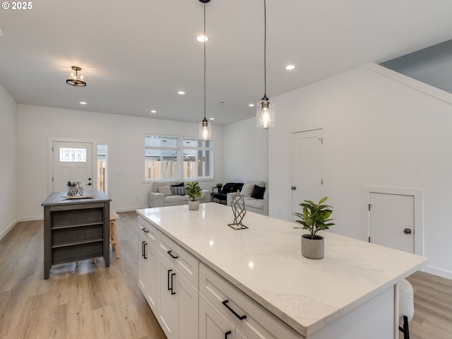 kitchen featuring white cabinets, open shelves, hanging light fixtures, light wood-style flooring, and a center island