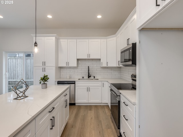 kitchen featuring a sink, stainless steel appliances, recessed lighting, white cabinetry, and tasteful backsplash
