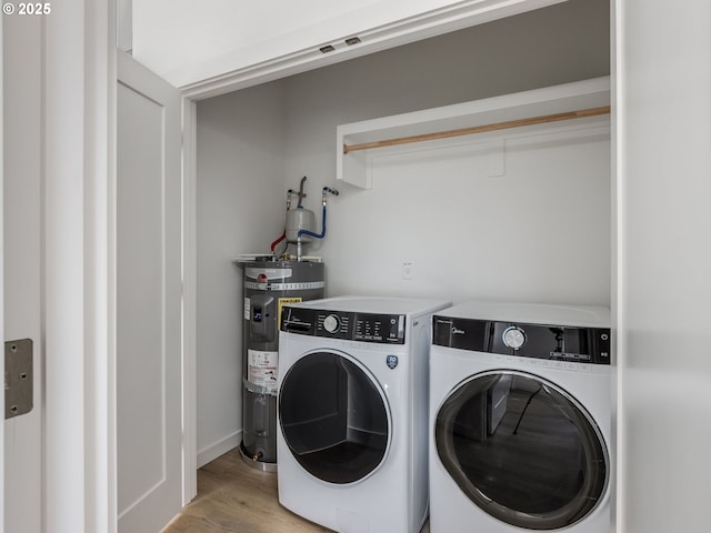 laundry room featuring laundry area, washer and clothes dryer, light wood-style flooring, and electric water heater