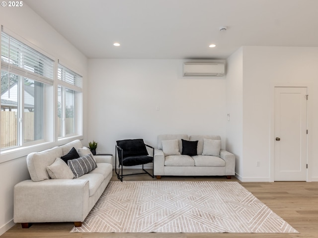 living area featuring recessed lighting, baseboards, a wall unit AC, and light wood-type flooring