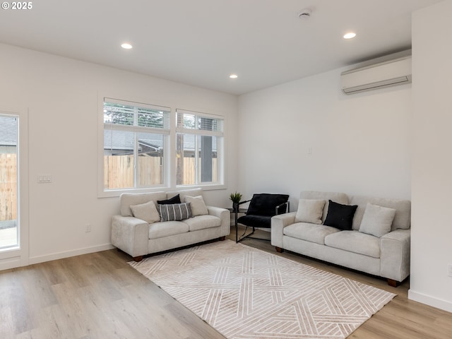 living area with baseboards, light wood-style flooring, recessed lighting, and a wall mounted air conditioner