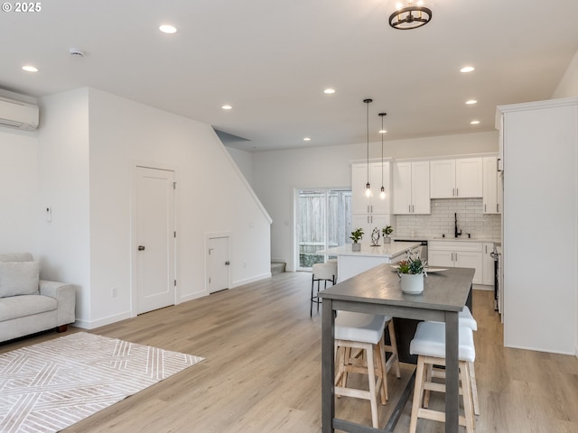 dining space with baseboards, a wall mounted air conditioner, recessed lighting, and light wood-style flooring