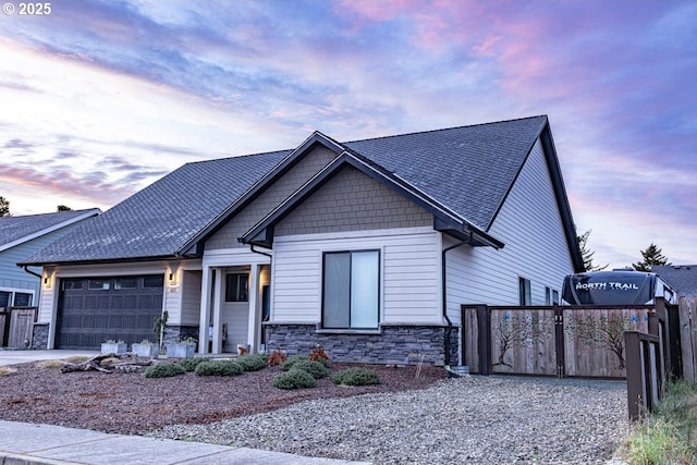 view of front of home with a garage, stone siding, fence, and concrete driveway