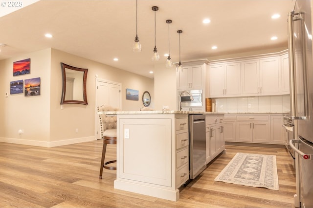 kitchen featuring an island with sink, a breakfast bar area, light wood-style flooring, and recessed lighting