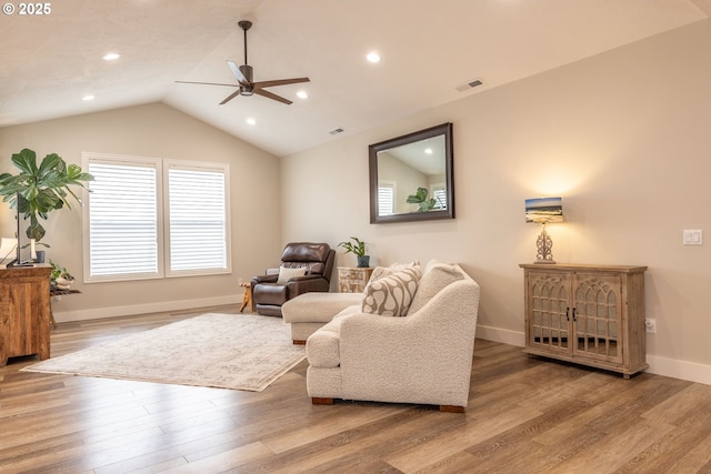 living room featuring wood finished floors, a ceiling fan, visible vents, vaulted ceiling, and baseboards