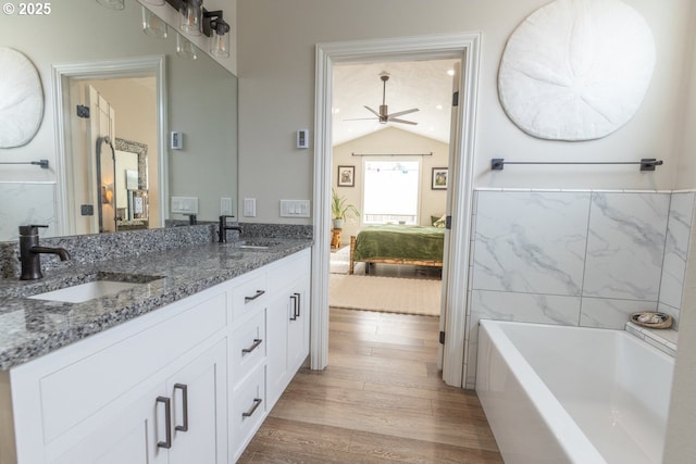 ensuite bathroom featuring ensuite bath, vaulted ceiling, a sink, and wood finished floors