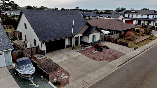 view of front facade featuring a garage, fence, driveway, roof with shingles, and a residential view