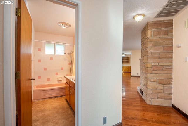 corridor featuring a textured ceiling and light hardwood / wood-style flooring