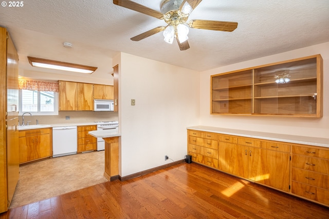 kitchen with sink, a textured ceiling, white appliances, and light hardwood / wood-style floors