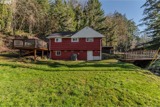 back of property with a wooden deck, a yard, and central air condition unit