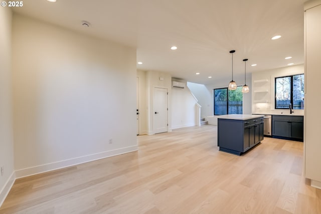 kitchen featuring a center island, decorative light fixtures, light countertops, a sink, and dishwasher