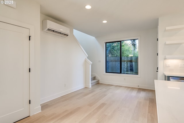 unfurnished living room featuring light wood-style flooring, recessed lighting, baseboards, stairway, and a wall mounted air conditioner