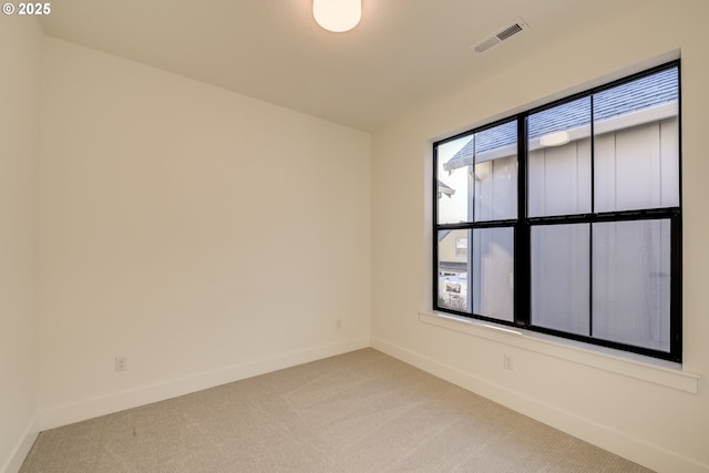 unfurnished room featuring baseboards, visible vents, and light colored carpet