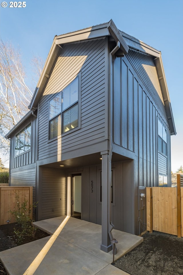 back of property featuring board and batten siding and fence