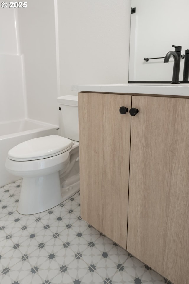 bathroom with toilet, vanity, and tile patterned floors