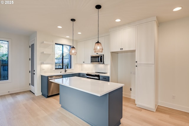 kitchen with white cabinets, stainless steel appliances, light countertops, and a center island