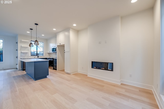 kitchen featuring white cabinets, a center island, hanging light fixtures, light countertops, and open shelves