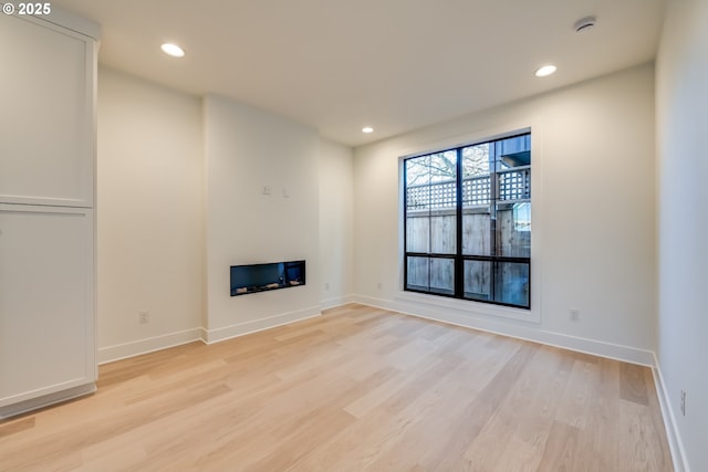 unfurnished living room with a glass covered fireplace, light wood-style flooring, and recessed lighting