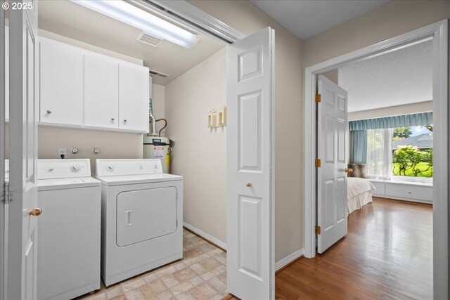 31560 SW Arbor Glen Loop, Wilsonville, OR 97070 - clothes washing area featuring visible vents, cabinet space, baseboards, water heater, and washer and dryer