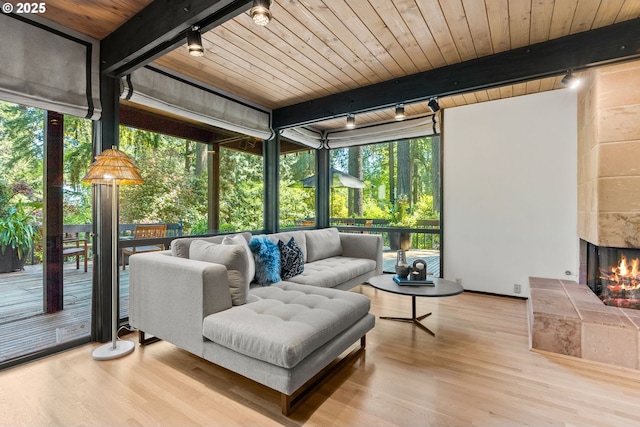 sunroom / solarium with track lighting, beam ceiling, and an outdoor living space with a fireplace
