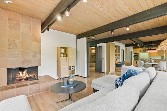 living room with rail lighting, wooden ceiling, beamed ceiling, wood finished floors, and a fireplace