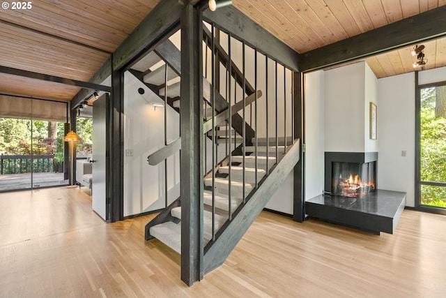 staircase featuring wooden ceiling, a multi sided fireplace, beam ceiling, and wood finished floors
