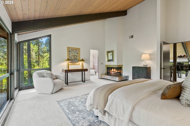 bedroom featuring carpet floors, beam ceiling, multiple windows, a multi sided fireplace, and wooden ceiling