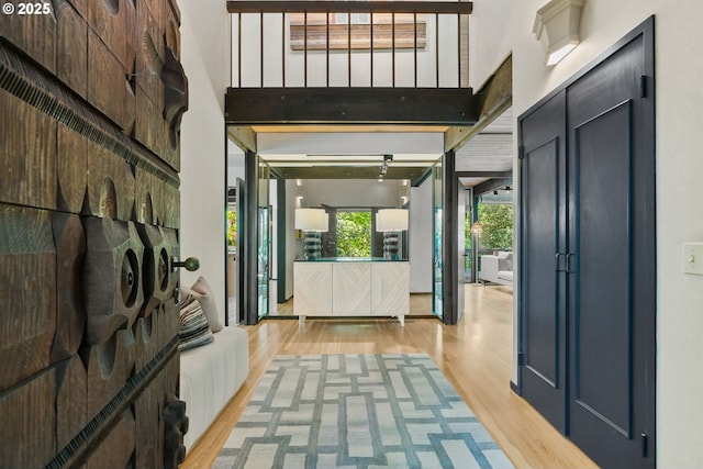 corridor featuring light wood-style floors and a towering ceiling