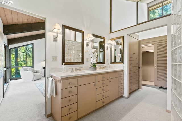 bathroom with plenty of natural light, beam ceiling, double vanity, a high ceiling, and wood ceiling