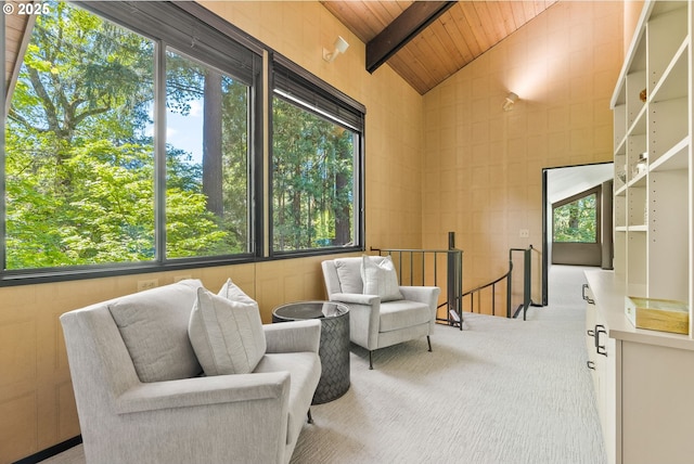 living area with wooden ceiling, plenty of natural light, an upstairs landing, carpet flooring, and beamed ceiling